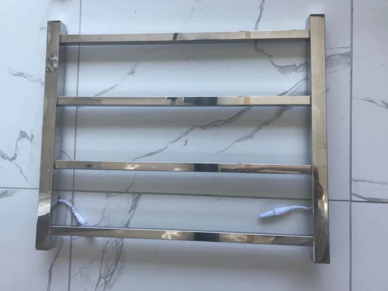 Silver square heated towel rail with four bars on tiled floor.