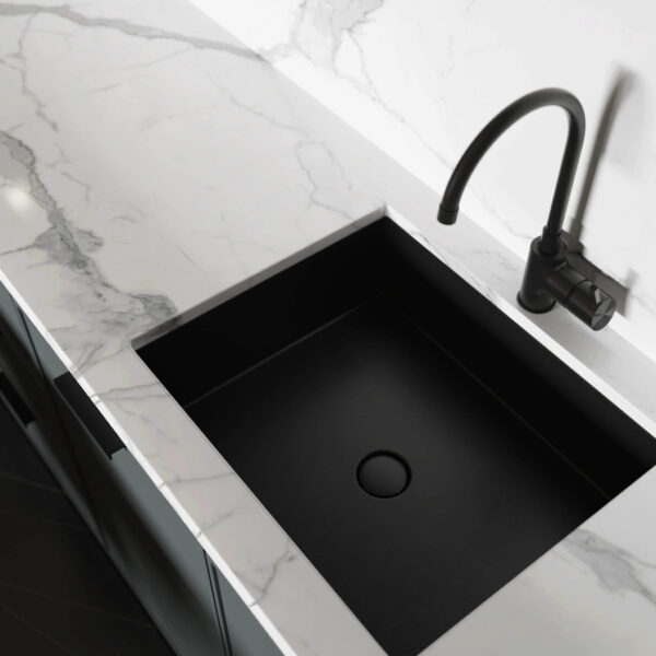 Modern kitchen with black sink and marble countertop.