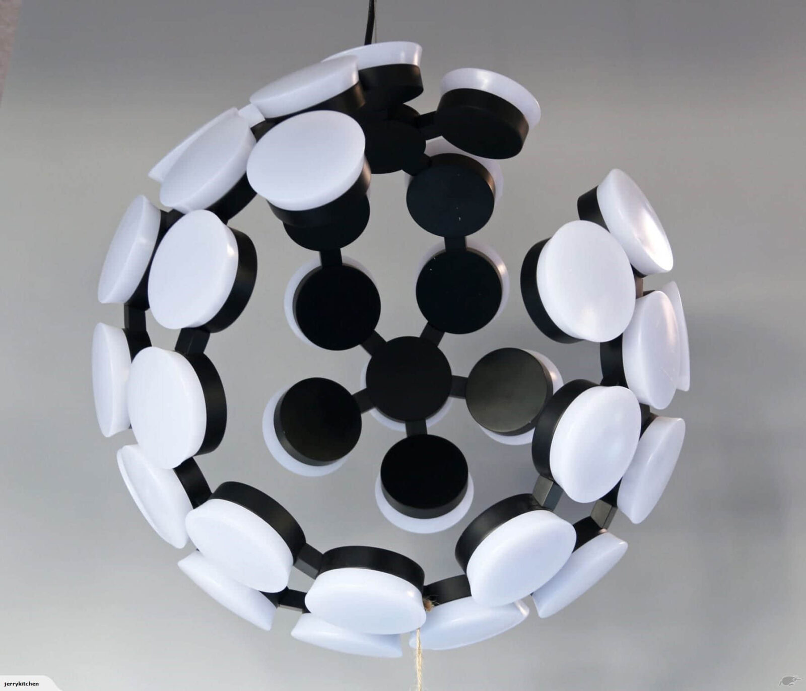 Modern spherical chandelier with black and white circular elements.