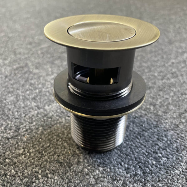 Bronze pop-up waste with overflow on carpeted floor.