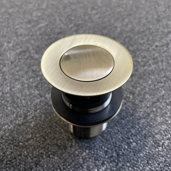 Bronze pop-up waste with overflow on textured surface.