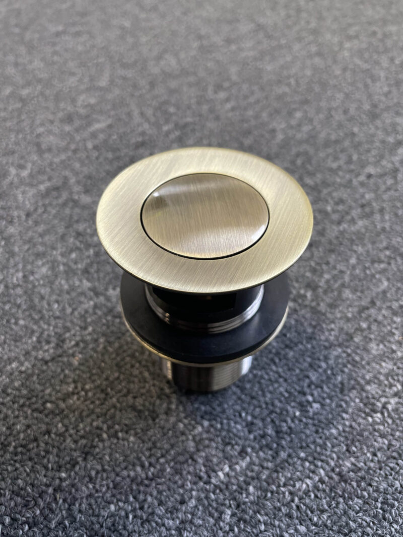 Bronze pop-up waste with overflow on textured surface.