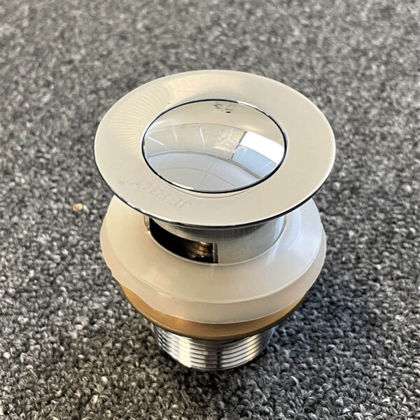 Chrome solid brass pop-up waste with overflow on gray surface.