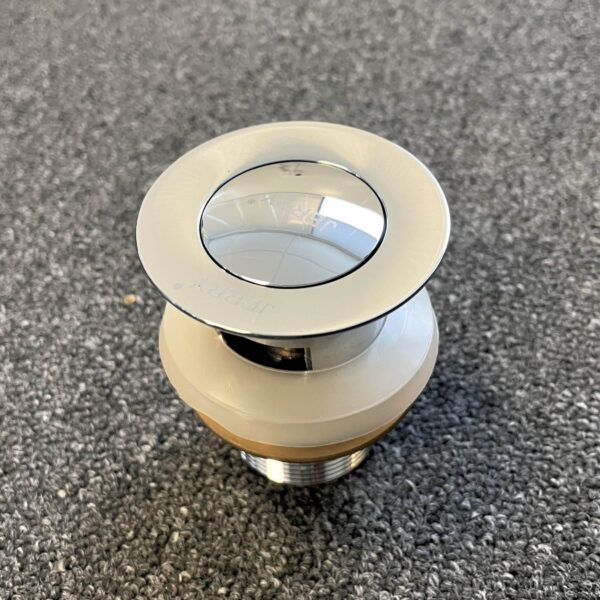 Chrome solid brass pop-up waste with overflow on gray surface.