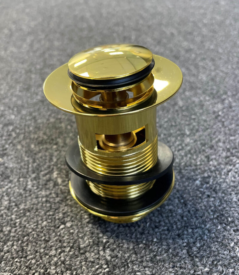 Gold pop-up waste with overflow on gray surface.