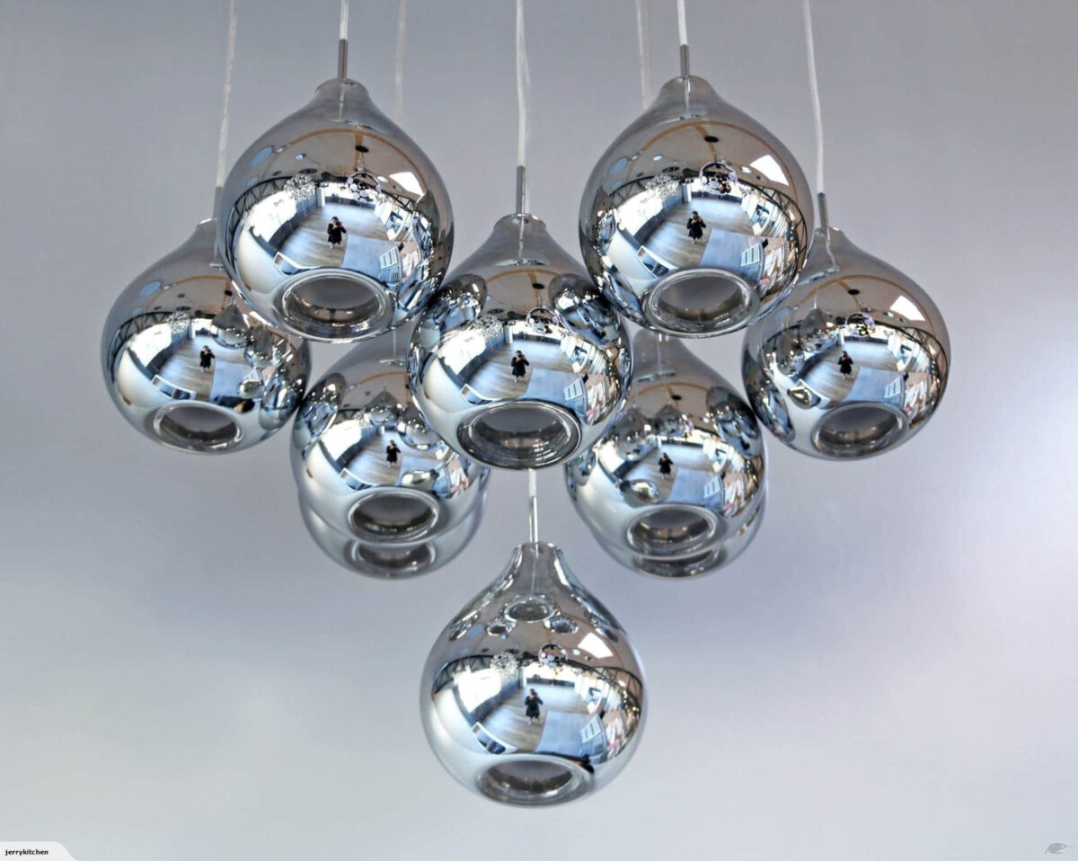 Cluster of modern chrome pendant lights against a white ceiling.