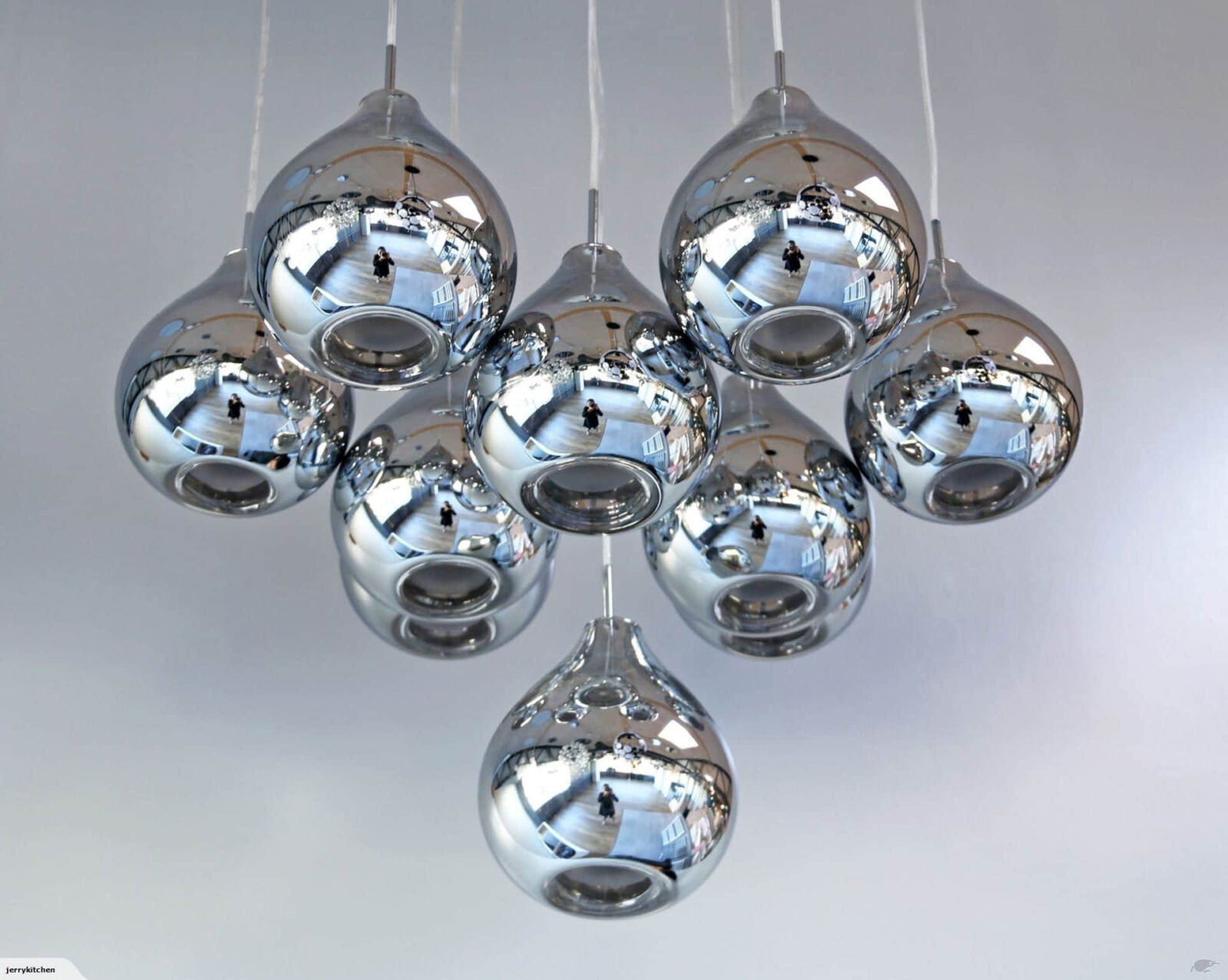 Cluster of modern chrome pendant lights against a white ceiling.