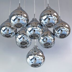 Cluster of modern chrome pendant lights against a white ceiling.