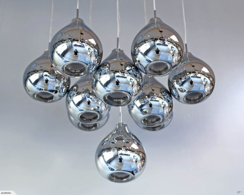 Cluster of modern chrome pendant lights against a white ceiling.