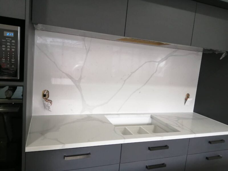 Calacatta Sky Quartz countertop and backsplash in modern kitchen setting.