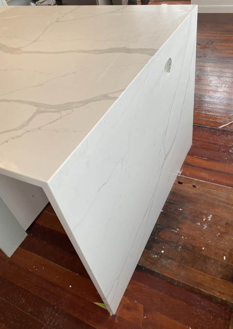 Calacatta Sky Quartz countertop with subtle veining on wooden floor.