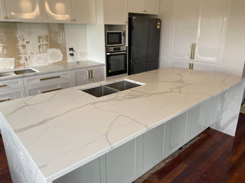Calacatta Sky Quartz kitchen countertop with sink, surrounded by white cabinets.