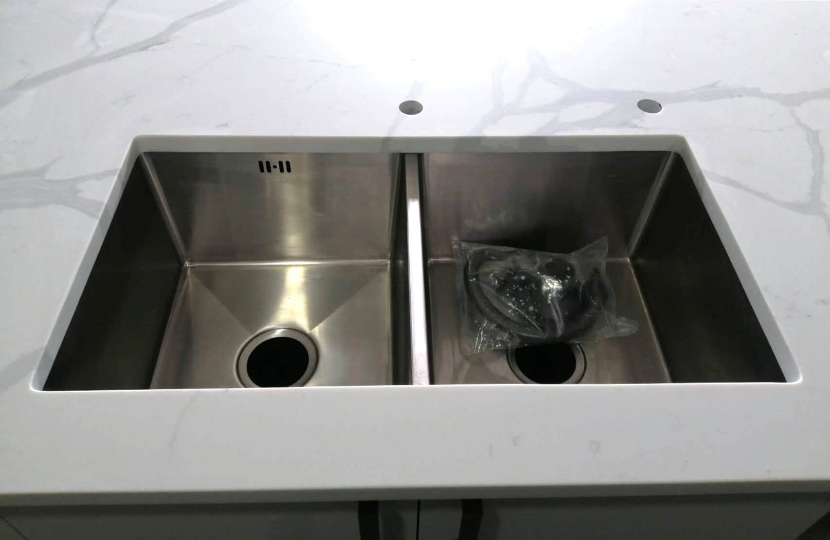Double stainless steel sink on Calacatta Sky Quartz countertop.