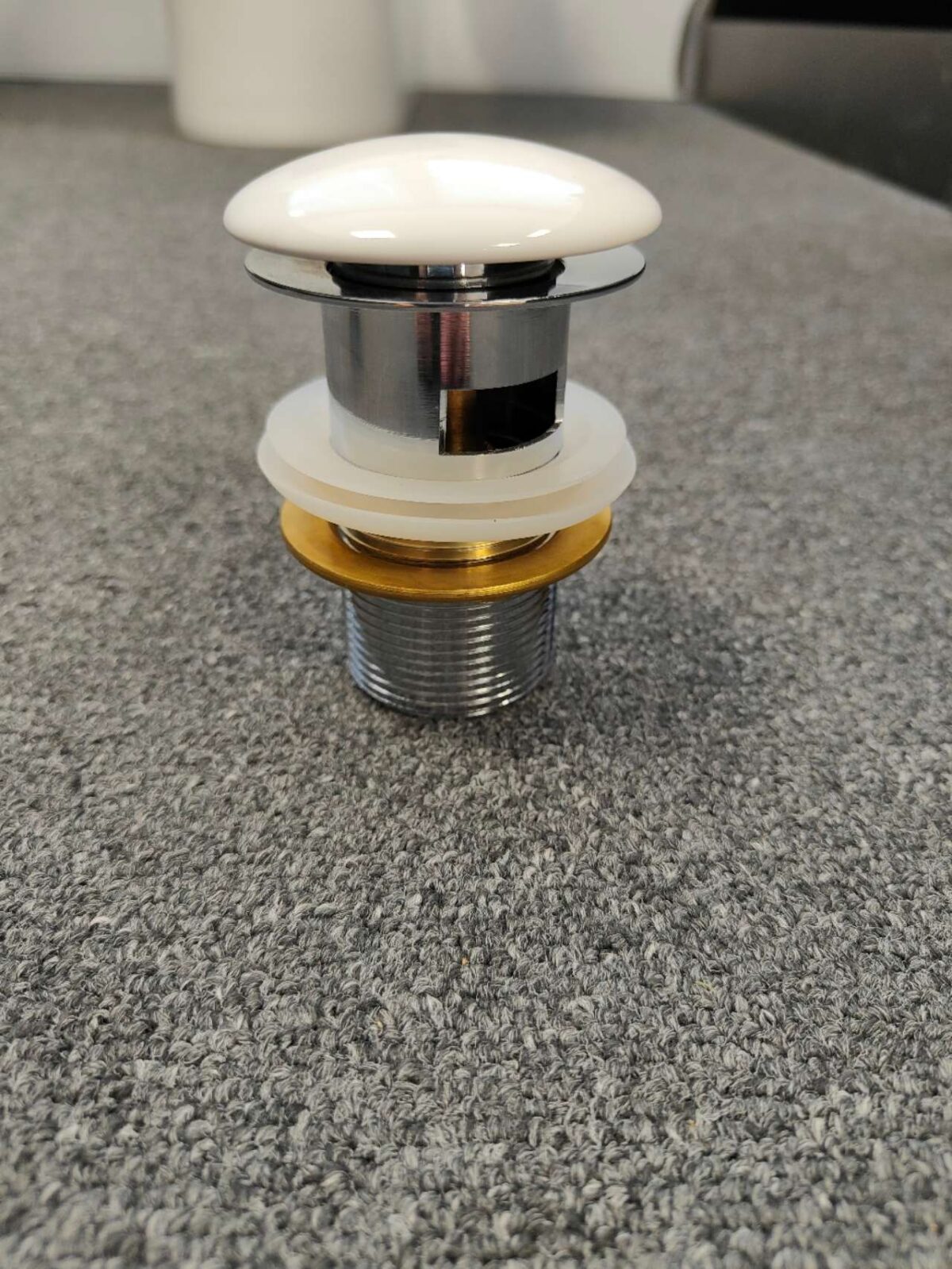 Ceramic pop-up waste on gray surface, Jerry Kitchen product.