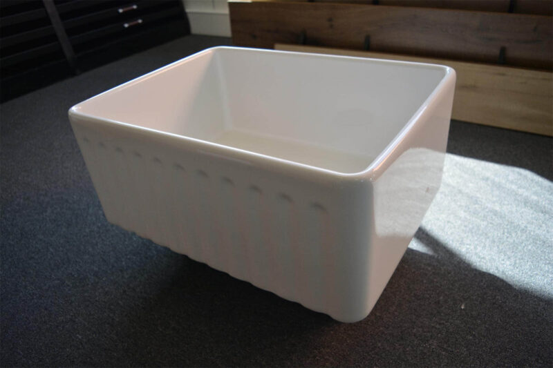 White ceramic kitchen sink on dark countertop.