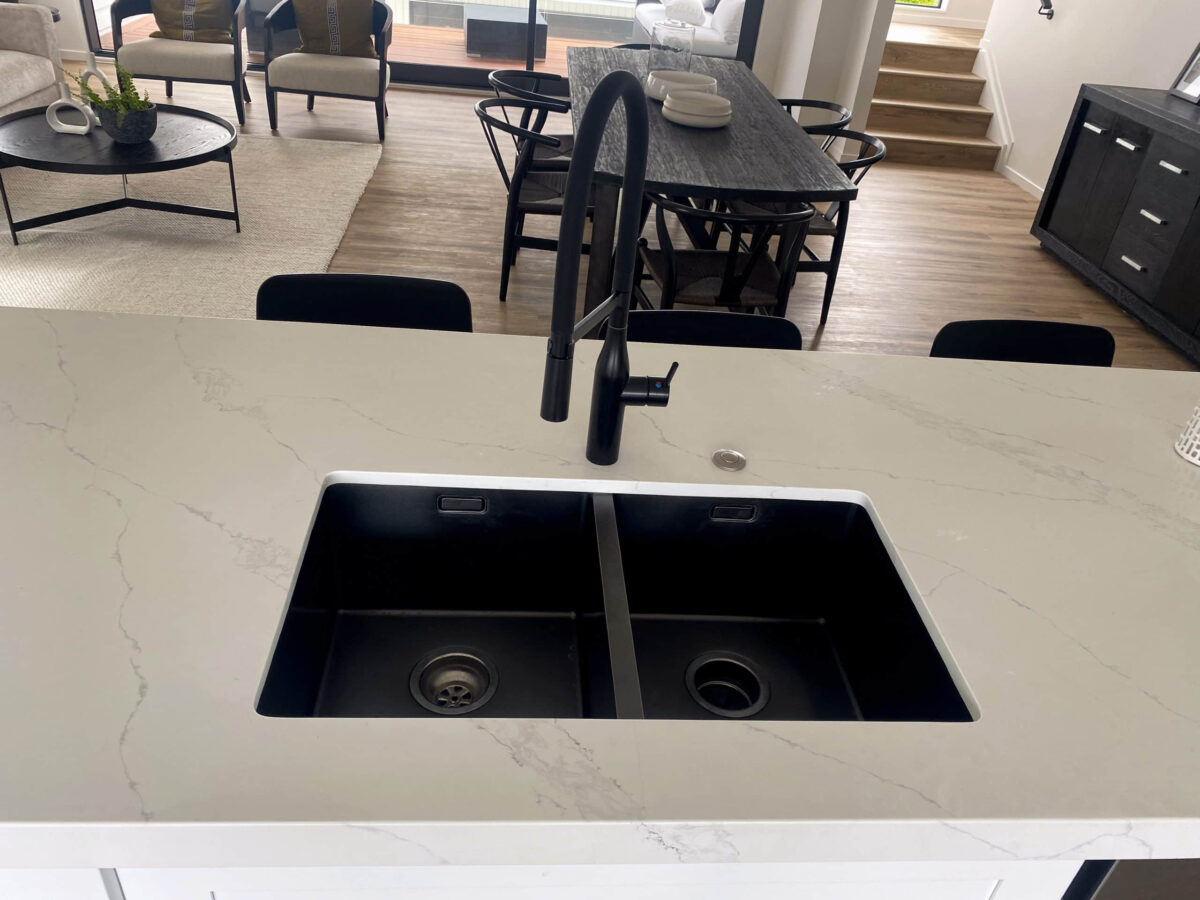 Modern kitchen sink with black faucet and marble countertop.