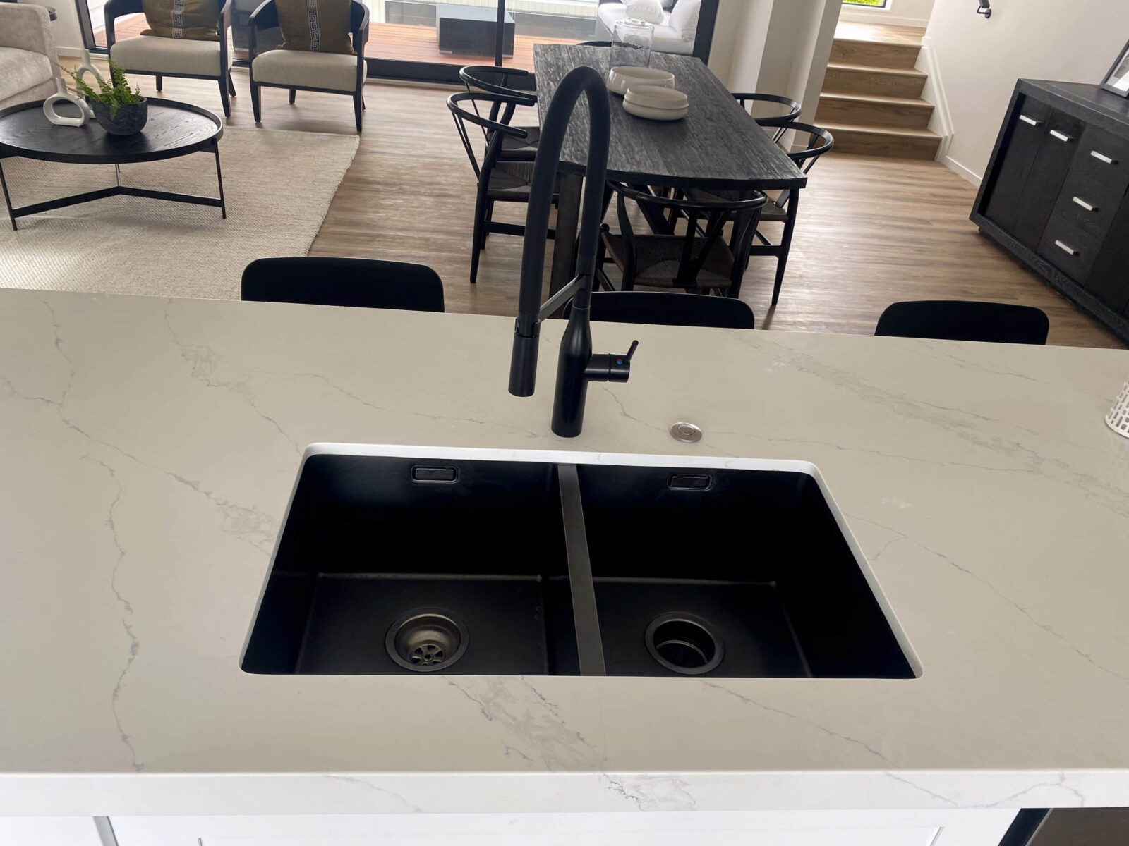 Modern kitchen sink with black faucet and marble countertop.