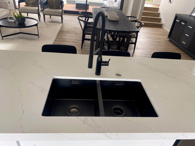 Modern kitchen sink with black faucet and marble countertop.