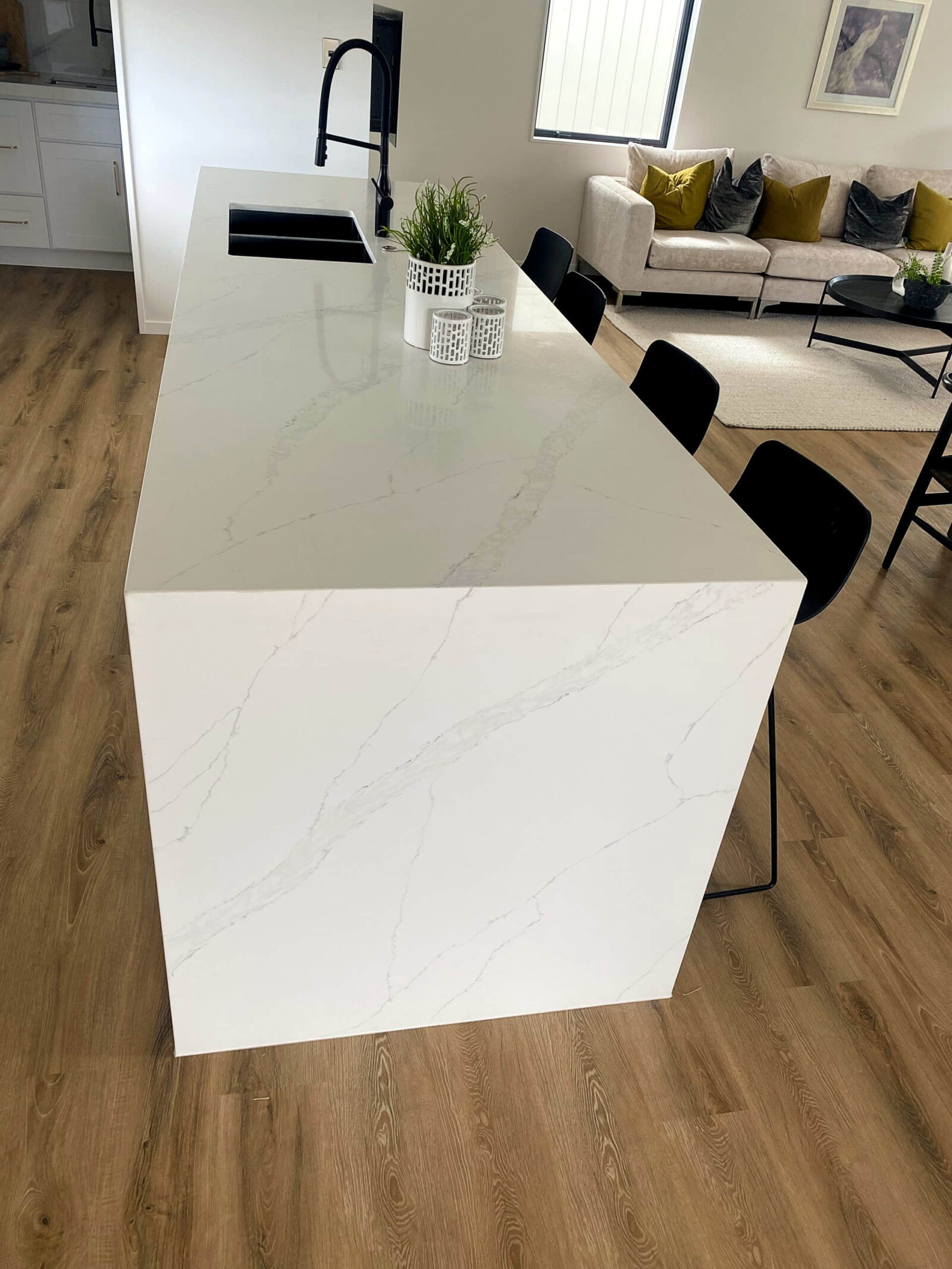 Modern kitchen island with white marble countertop and black chairs.