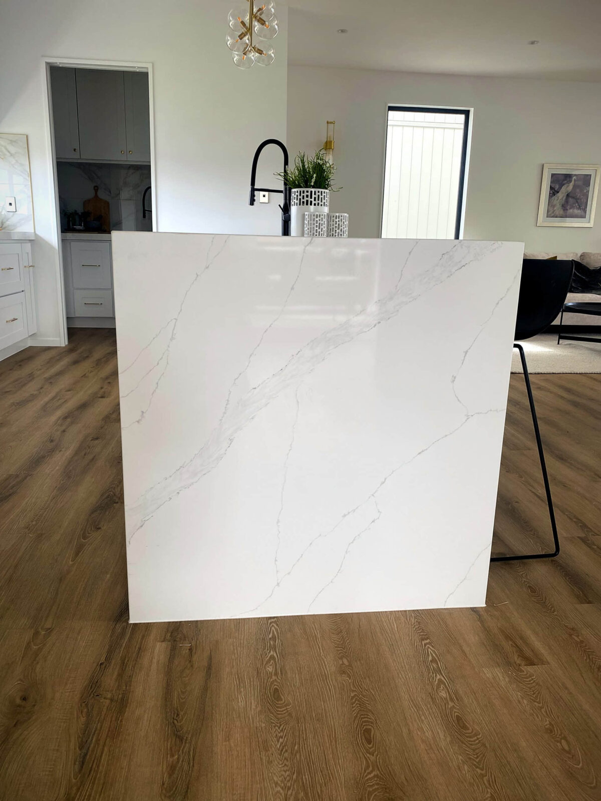 Modern kitchen with marble island and wooden flooring.