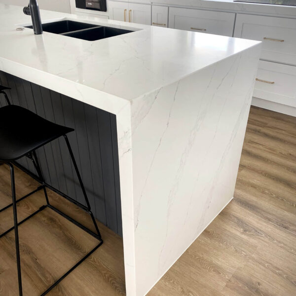 Modern kitchen with white marble countertop and black stool.