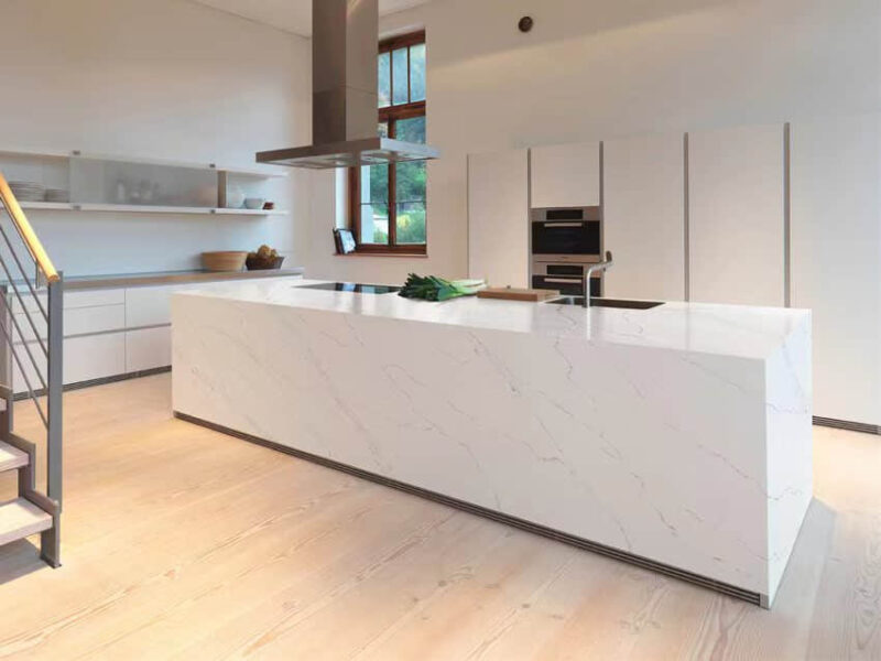 Modern kitchen with marble island and built-in appliances.