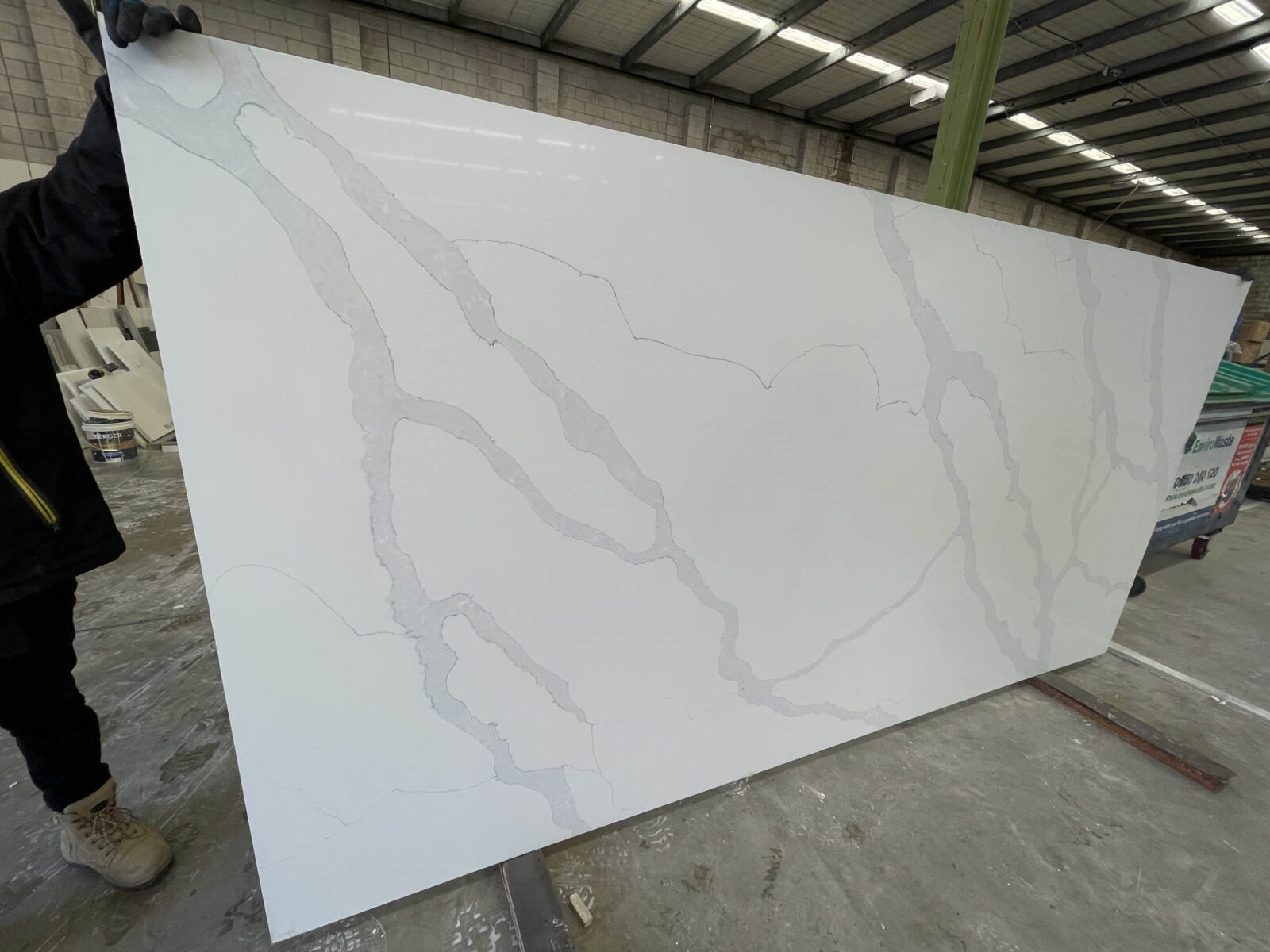 White marble slab with gray veining in a warehouse.