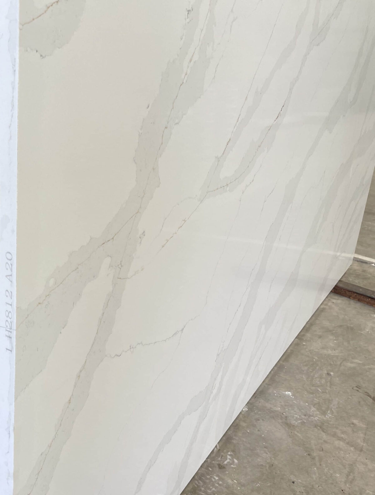 White marble slab with subtle gray veining, displayed in a showroom.