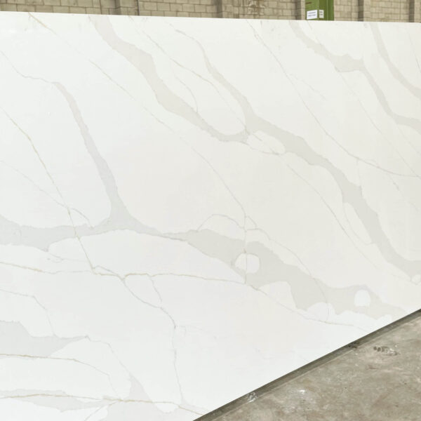 White marble slab with subtle gray veining in a warehouse setting.