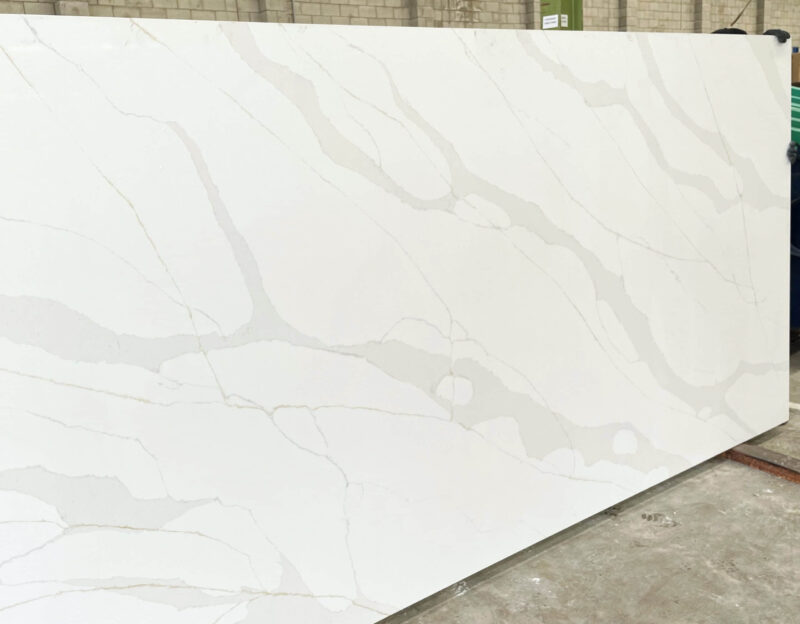 White marble slab with subtle gray veining in a warehouse setting.