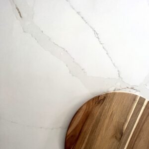 Marble countertop with wooden cutting board, showcasing Carrara Golden design.