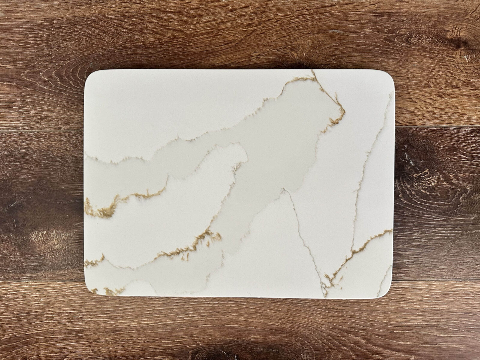 Marble-patterned rectangular cutting board on wooden surface.