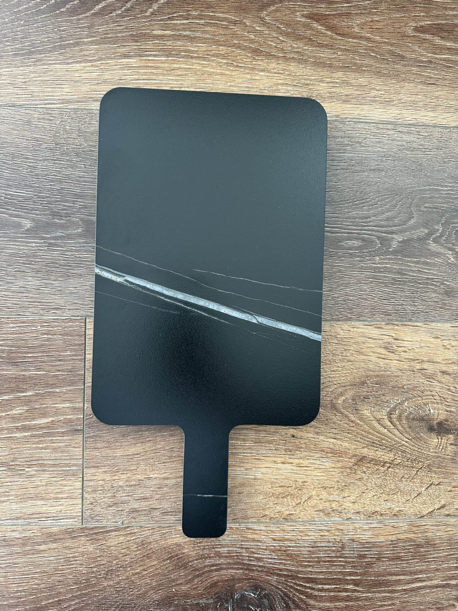 Black marble cutting board on wooden surface.