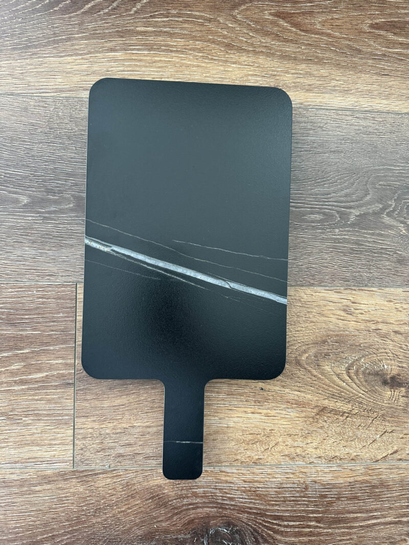 Black marble cutting board on wooden surface.