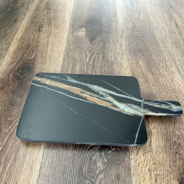 Black marble cheese board on wooden floor.