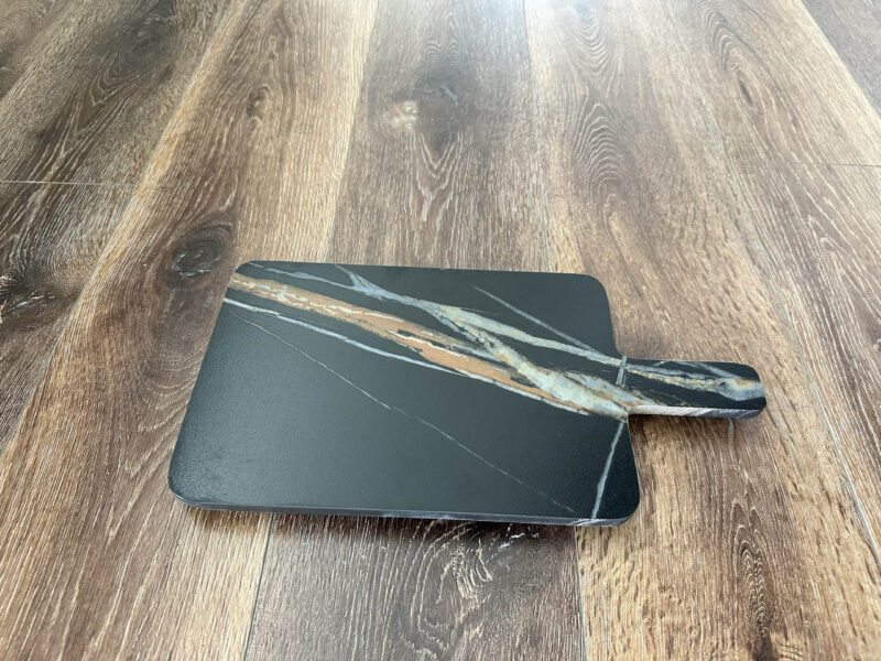 Black marble cheese board on wooden floor.