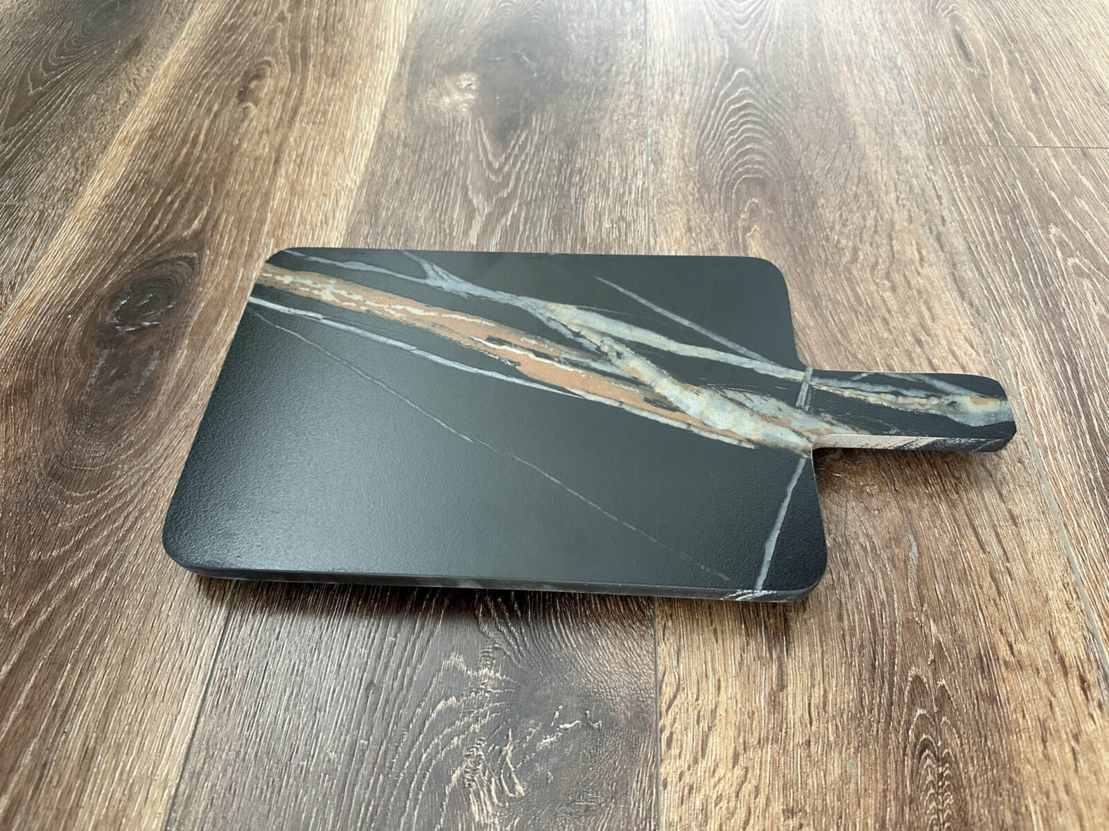 Marble cheese board on wooden floor.