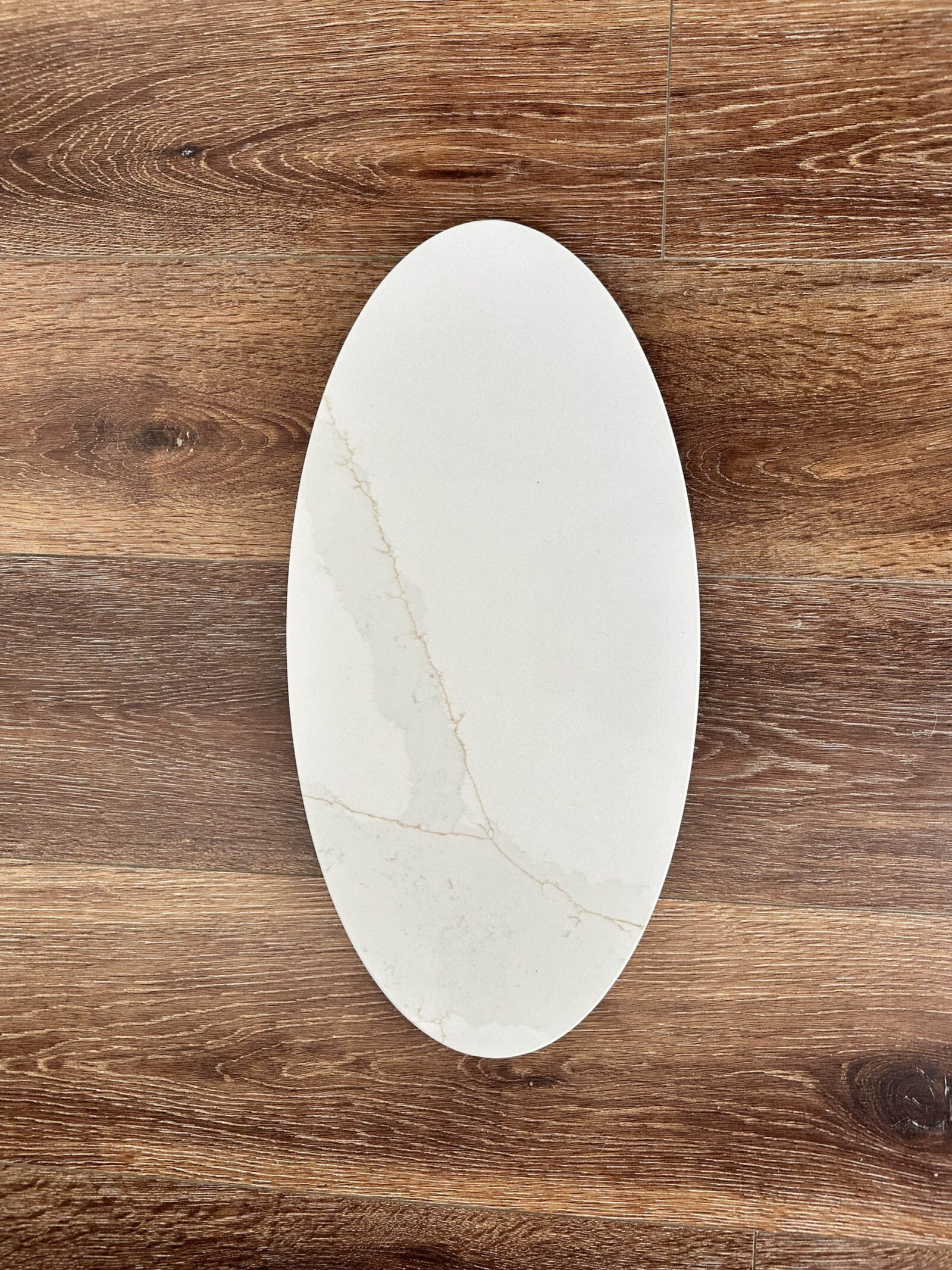 Oval marble plate on wooden table background.