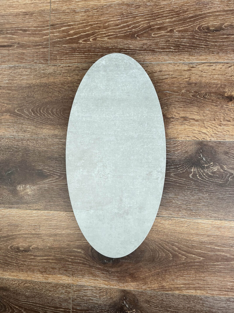Oval-shaped ceramic plate on wooden floor background.