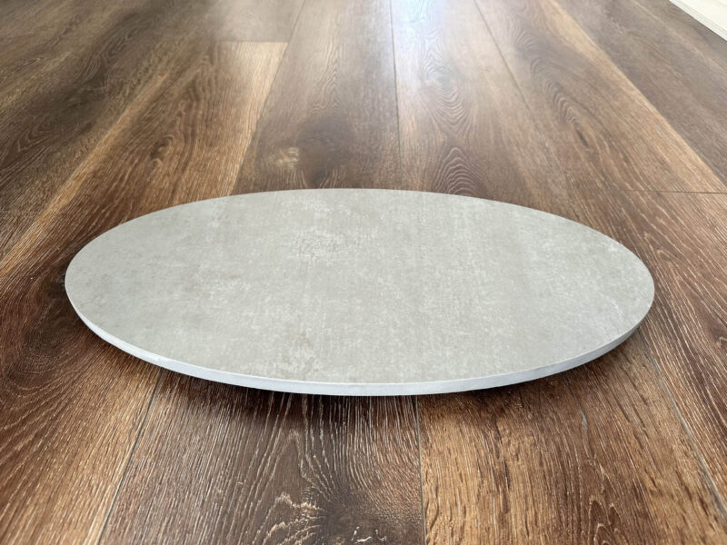 Round stone pizza oven base on wooden floor.