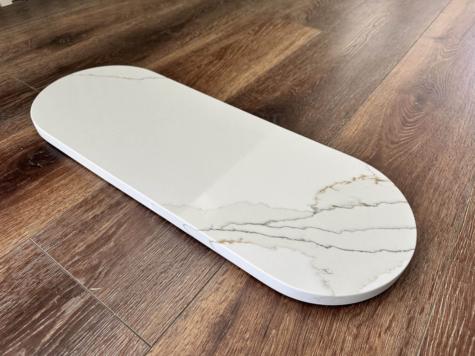 Marble cutting board on wooden kitchen floor.