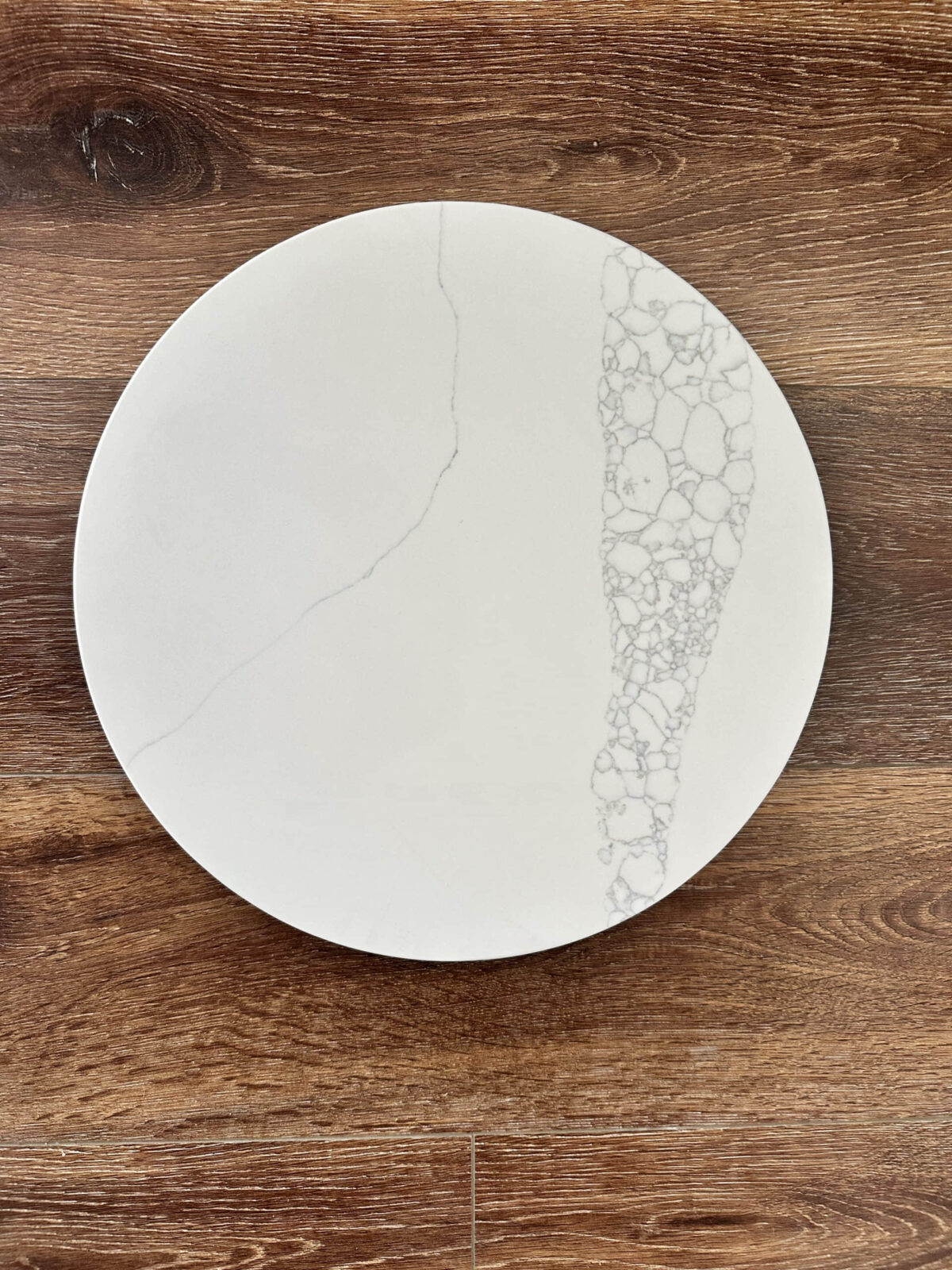 White marble plate with intricate pattern on wooden surface.
