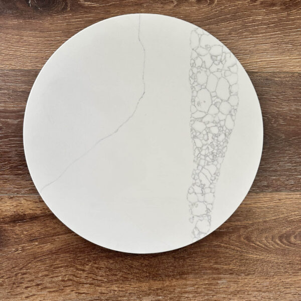 White marble plate with intricate pattern on wooden surface.