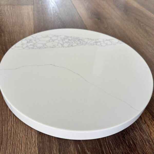 Round marble cutting board on wooden floor.