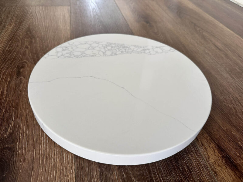Round marble cutting board on wooden floor.