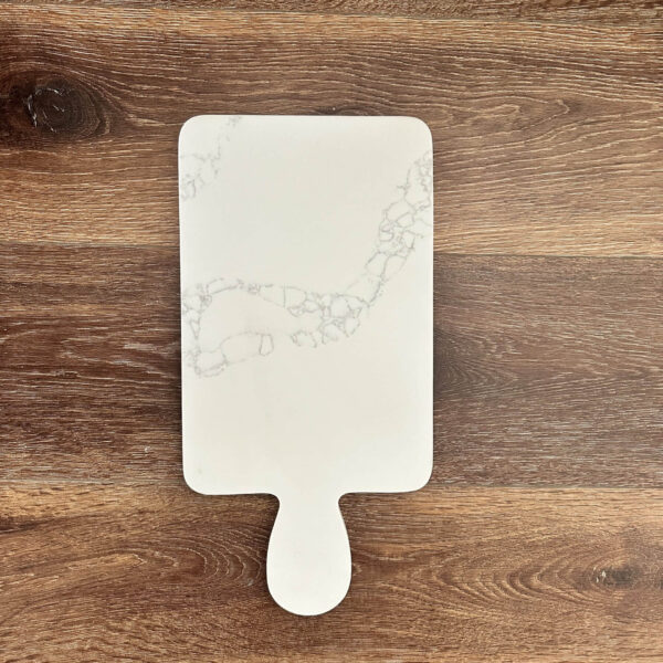 Marble-patterned cutting board on wooden surface.