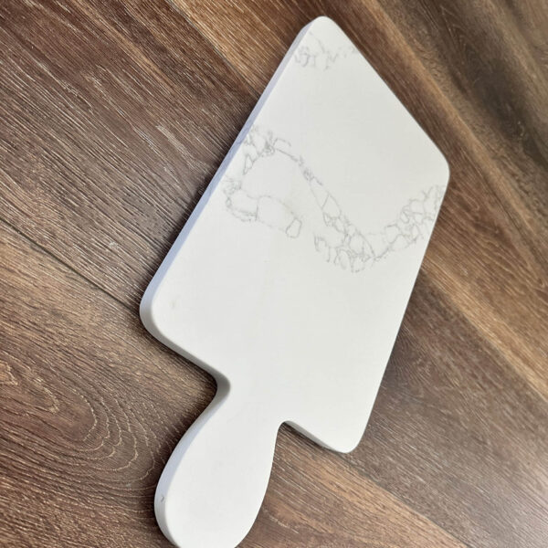 Marble-patterned cutting board on wooden floor.