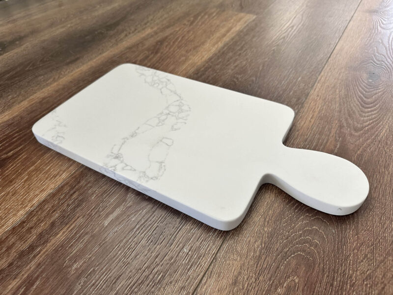 White marble cutting board on wooden floor.