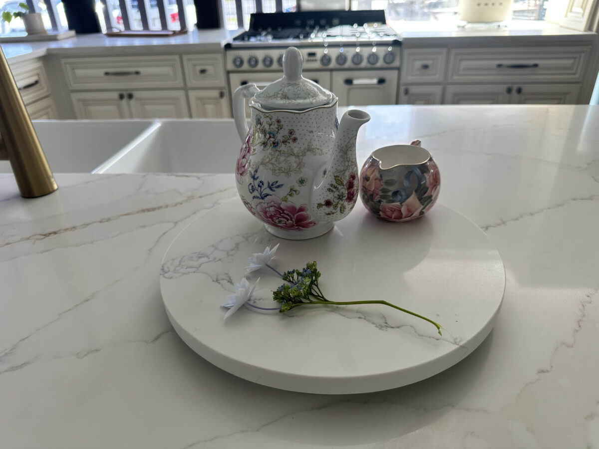 Floral teapot and creamer on marble kitchen counter.