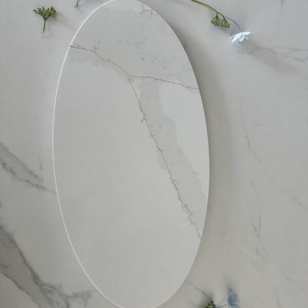 Oval marble platter on marble surface with scattered small flowers.